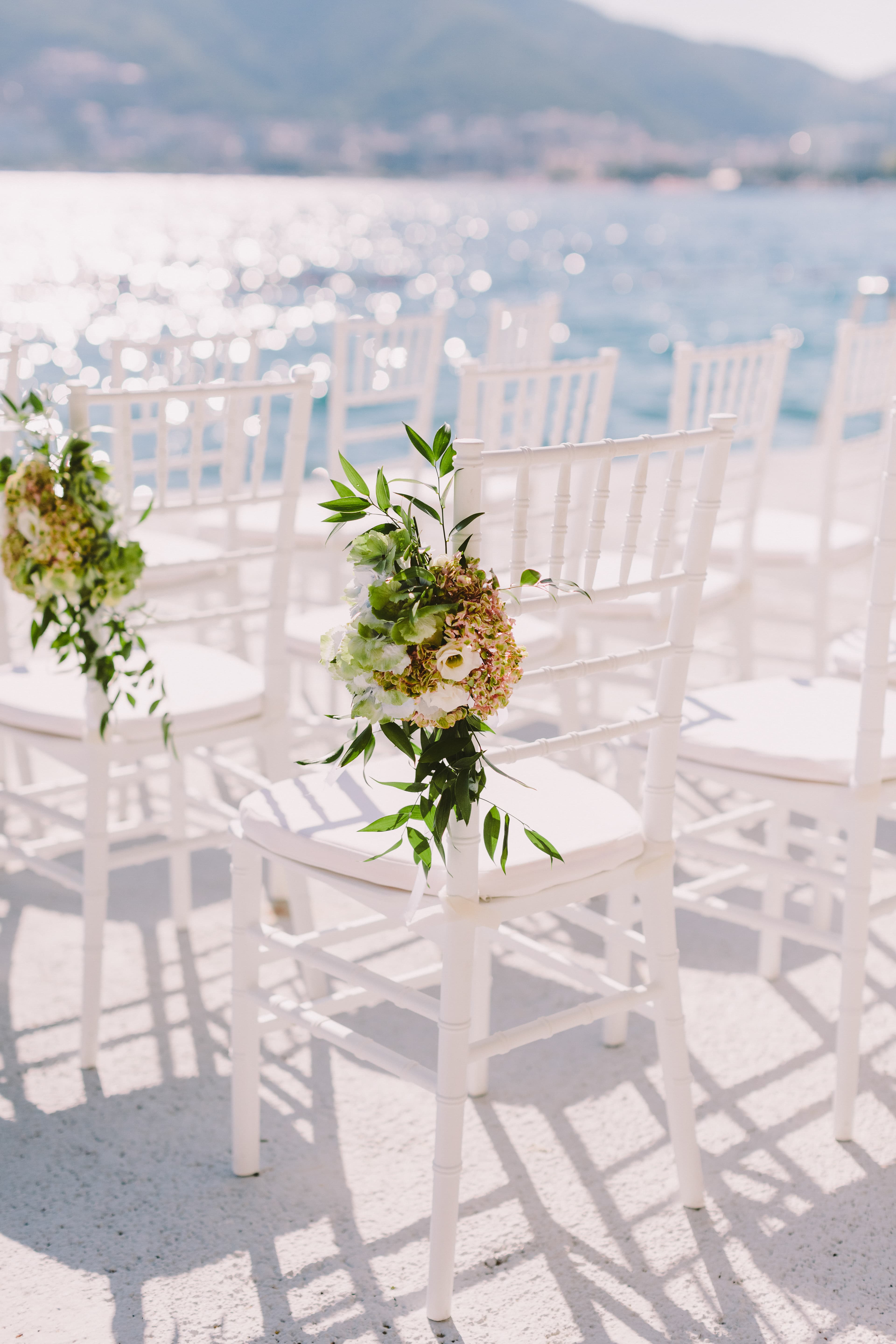 Sillas blancas decoradas con flores frente al mar para una ceremonia de boda en Mallorca